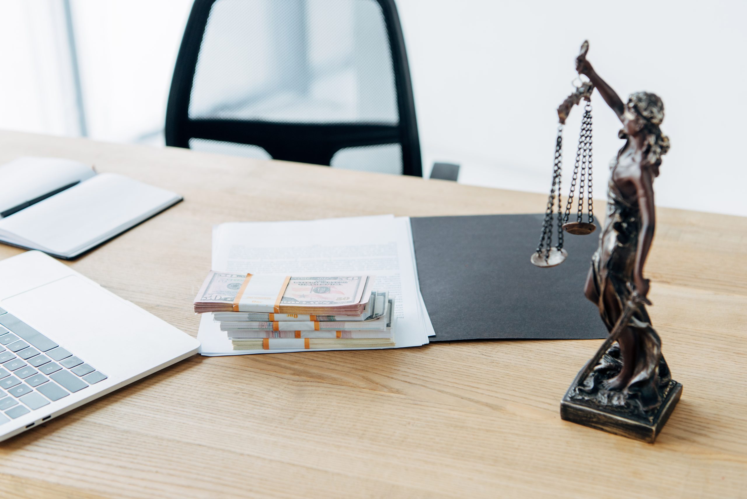 selective focus of money on folder with documents near statuette of justice