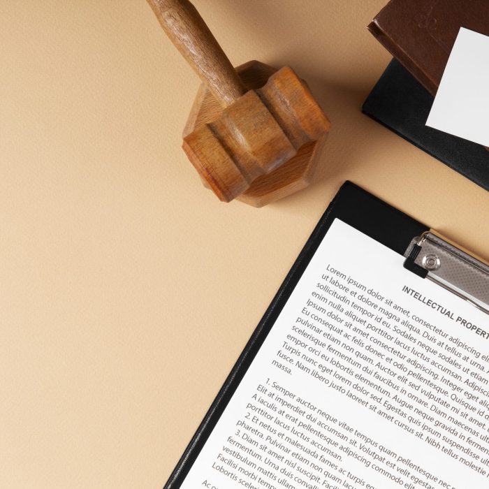 Drewniany młotek sędziowski, dokument z napisem „Intellectual Property Agreement” i symbol praw autorskich.
